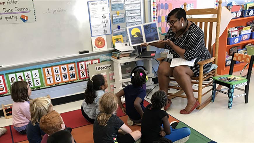 Photo of a teacher reading a book to students