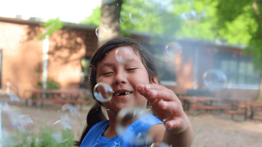Photo of a little girl playing with bubbles outside