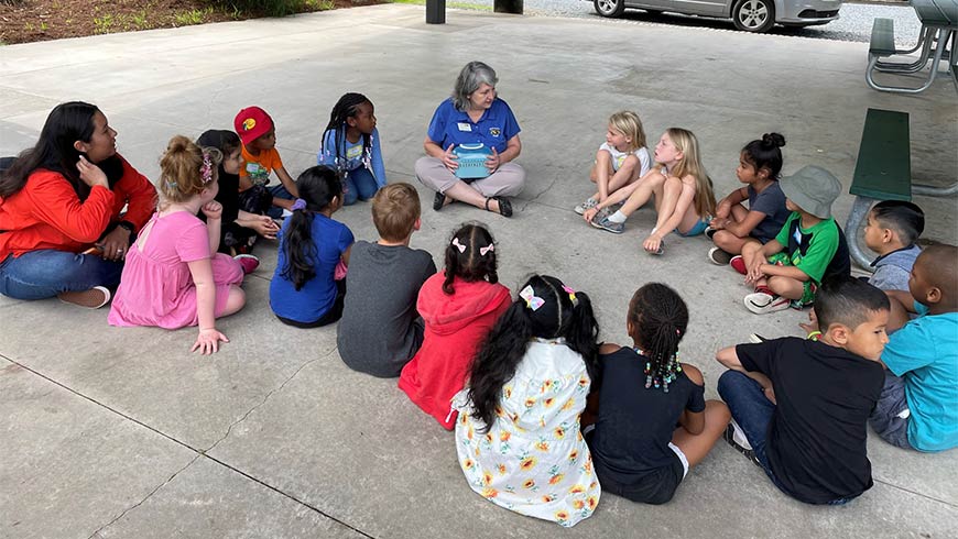 Photo Of Children And Their Teacher Sitting Outside At Fayetteville Street Elementary