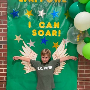 Photo of a child standing against a wall with wings on it